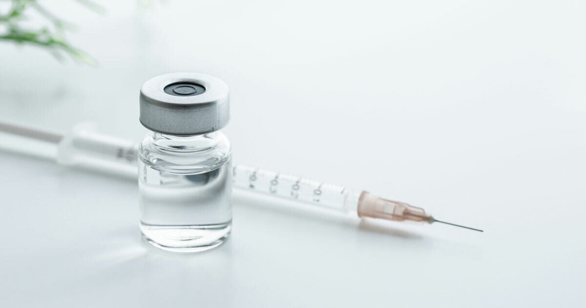 Image of a syringe next to a clear bottle of medication