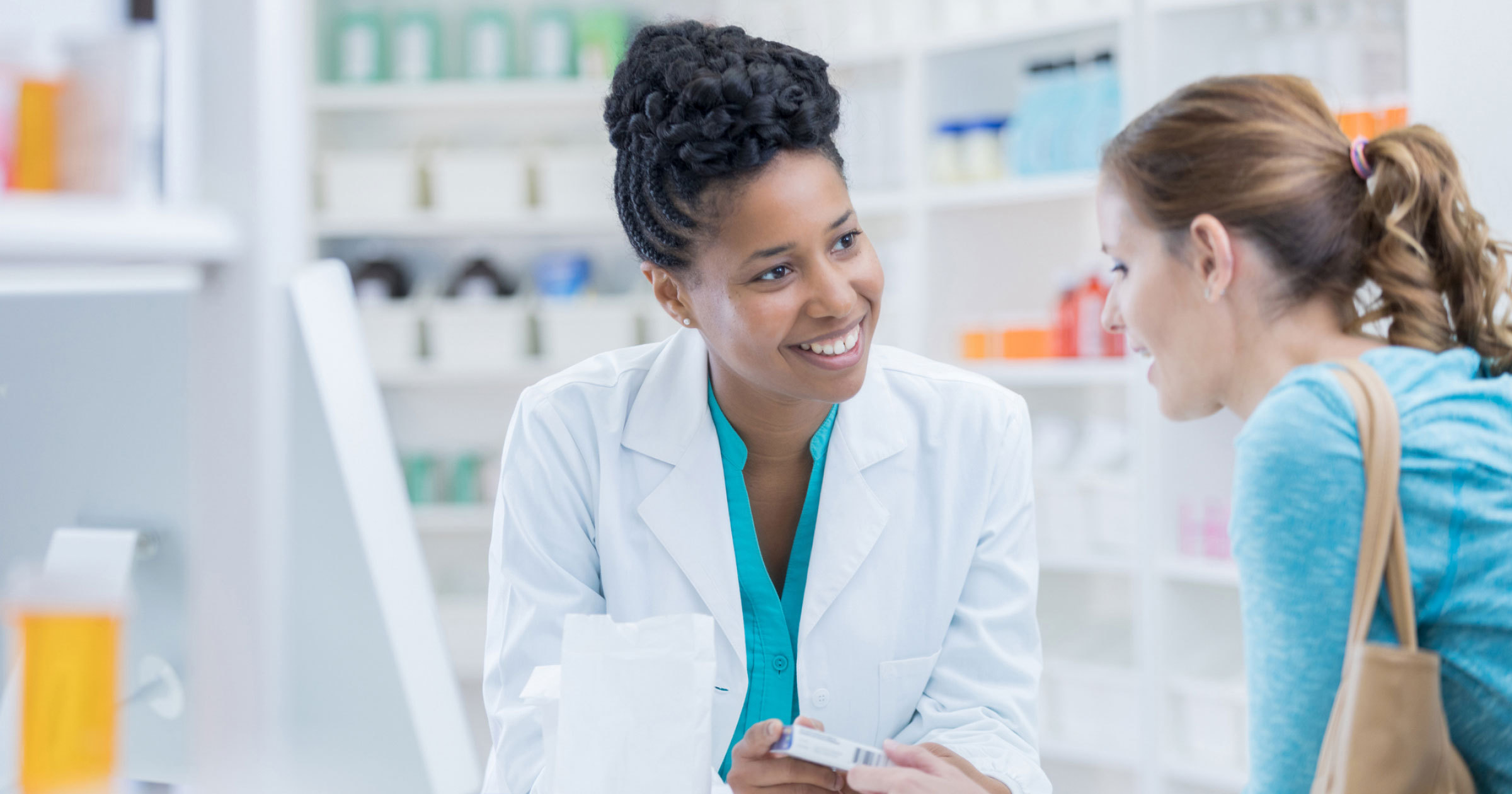 A photo of a woman talking to a pharmacist about their medication instructions.